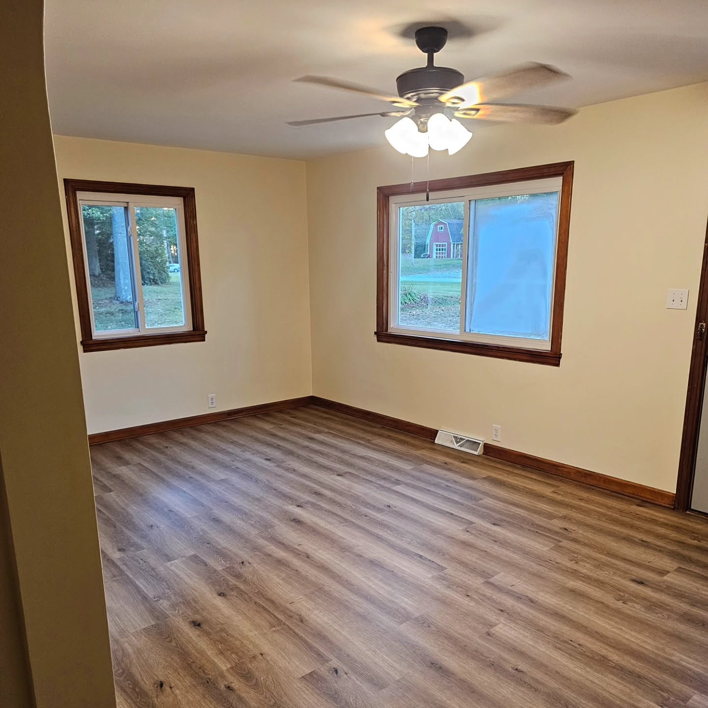 Same room with freshly painted walls, new wood-look flooring, and stained window trim
