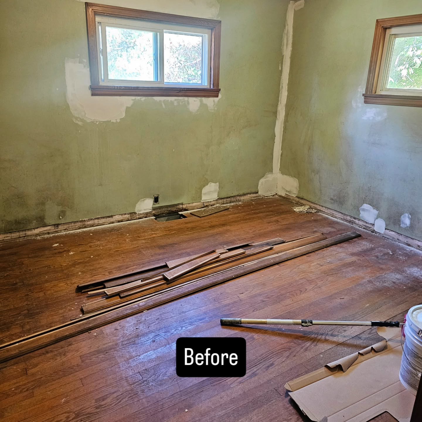 Worn room with patched green walls and torn-up flooring before renovation